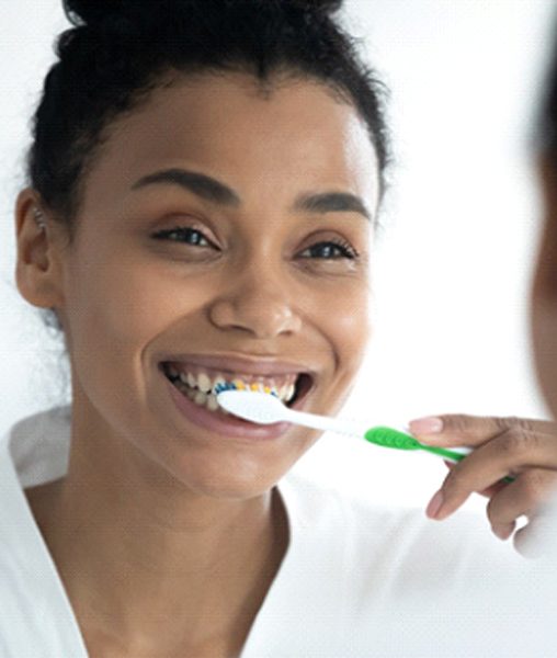 Happy woman brushing teeth to fight periodontal disease