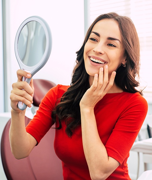 Woman looking at smile in mirror after makeover