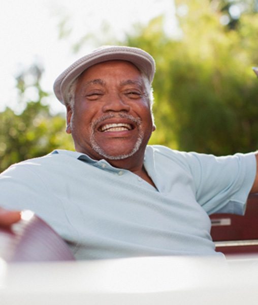 person smiling and sitting in his car with his arm on the wheel