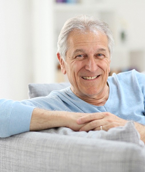 Closeup of man with dentures in York smiling on couch