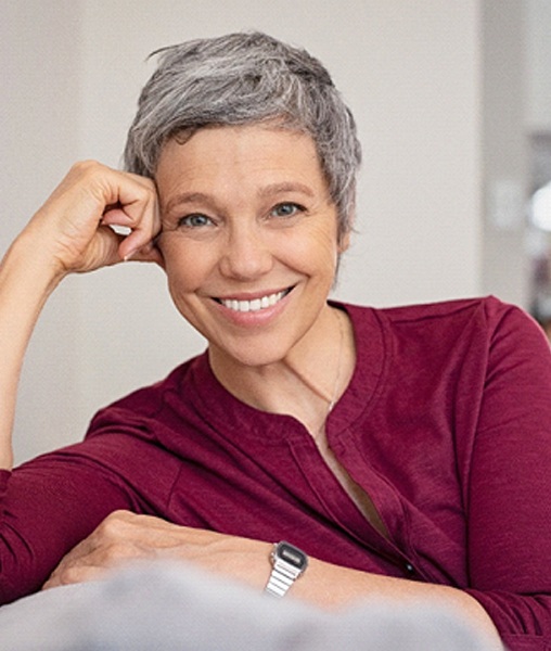 Woman with dentures in York smiling on couch