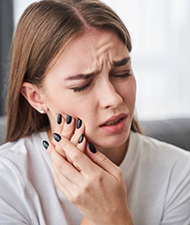 a woman holding her cheek due to a dental emergency