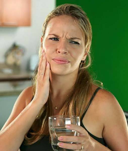 Woman with dental emergency in York holding glass of water