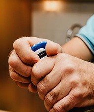 Closeup of man using bottle cap opener