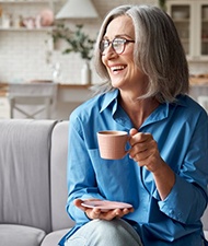 a woman smiling while enjoying a morning coffee