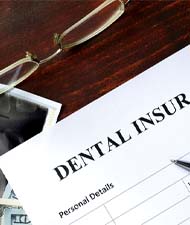 Dental insurance form next to money, glasses, and X-Ray