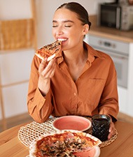 Woman smiling while enjoying pizza at home