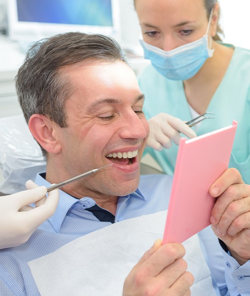 Man looking at smile after dental bridge placement