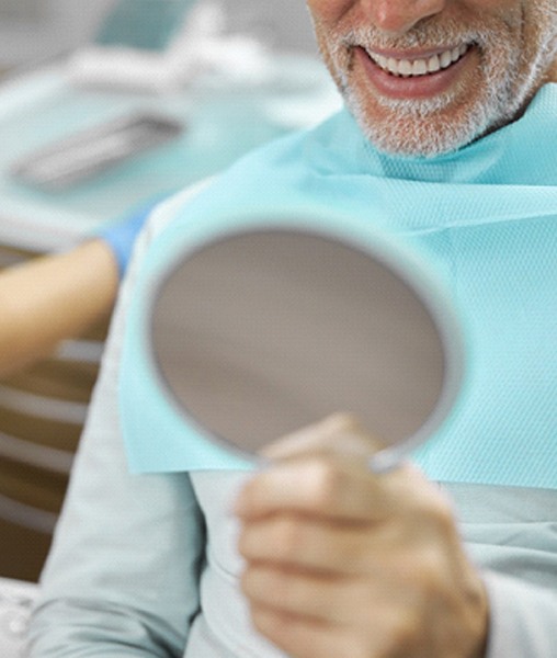 Senior man admiring his smile after receiving implant-retained dentures
