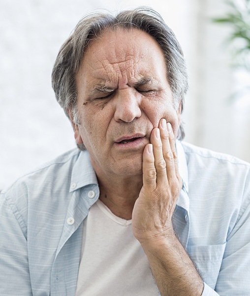 Man in need of T M J therapy holding jaw in pain