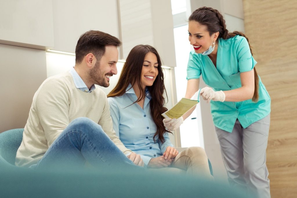 Couple smiling while reviewing dental insurance information with dentist