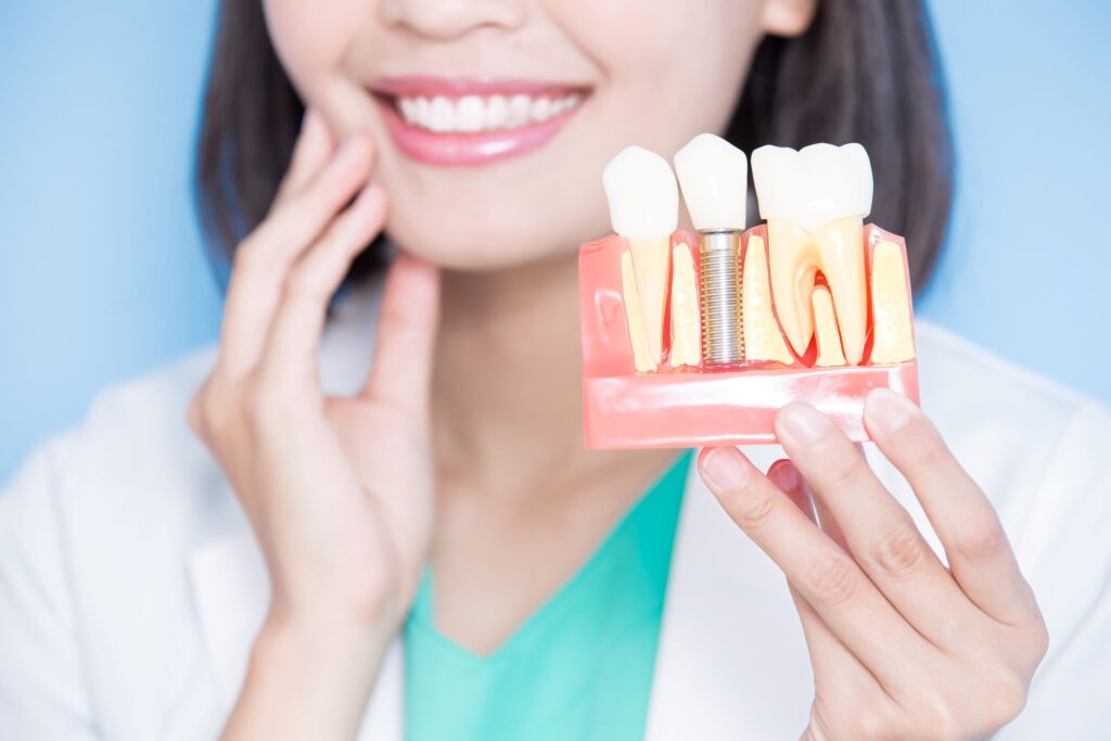 Nose-to-chest image of dentist touching her jaw and holding sample implant