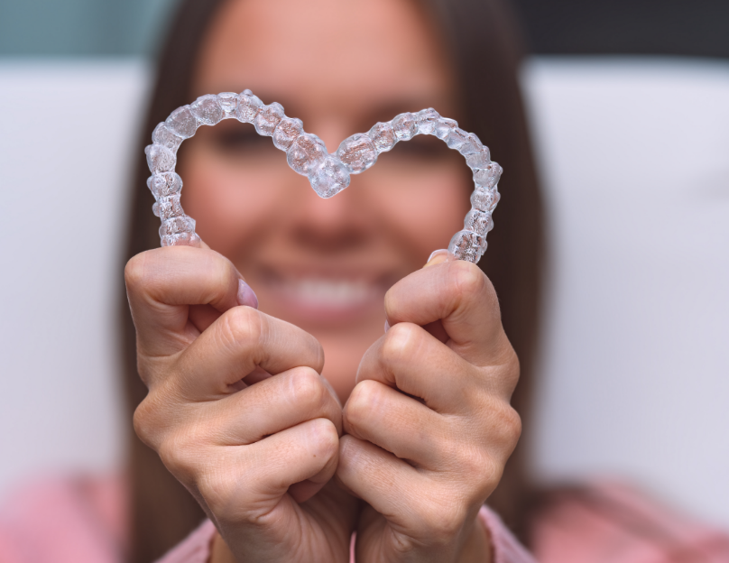 Woman holding Invisalign aligners in heart shape